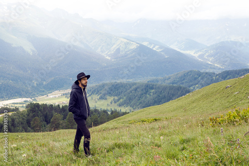 man with a beard shepherd standing in the mountains in a black raincoat in the rain © saulich84