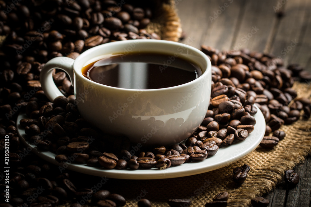 Coffee cup and beans on a rustic background. Coffee Espresso and a piece of cake with a curl. Cup of Coffee and coffee beans on table. Coffee cup and beans on a rustic background. Coffee Espresso and a piece of cake with a curl. Cup of Coffee and coffee beans on table.