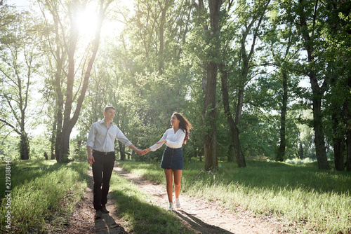 young couple walking in the forest  summer nature  bright sunlight  shadows and green leaves  romantic feelings