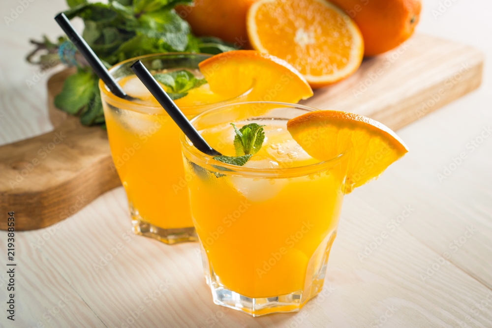 Photo of fresh orange juice in the glass jar. Summer healthy organic drink concept. Cold beverages with ice and orange fruits. Photo of fresh orange juice in the glass jar. Summer healthy organic drink concept. Cold beverages with ice and orange fruits.