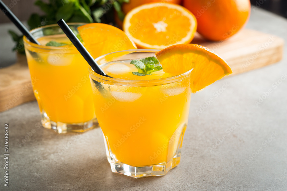 Photo of fresh orange juice in the glass jar. Summer healthy organic drink concept. Cold beverages with ice and orange fruits. Photo of fresh orange juice in the glass jar. Summer healthy organic drink concept. Cold beverages with ice and orange fruits.