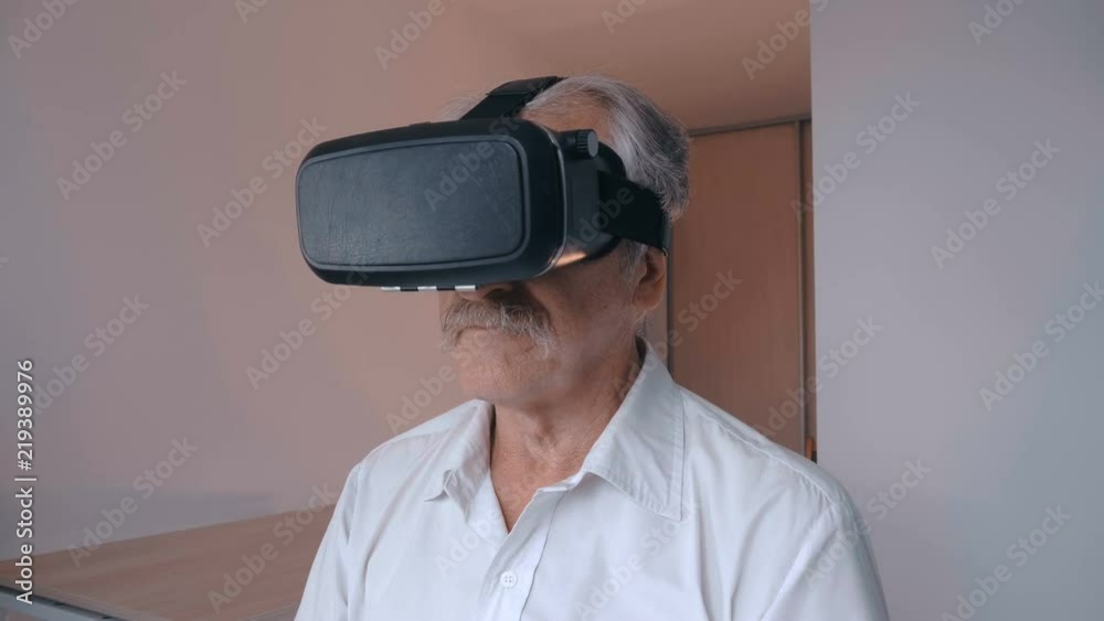 Senior man using his VR headset for watching the 360 video at home in living room Senior man using his VR headset for watching the 360 video at home in living room