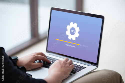 Man working and Installing update process with gearbox percentage progress and loading bar on laptop / computer screen at office