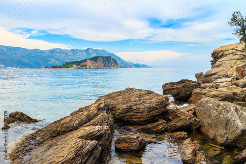 Mogren beach with big stones and Sveti Nikola island at Adriatic sea coastline in Montenegro