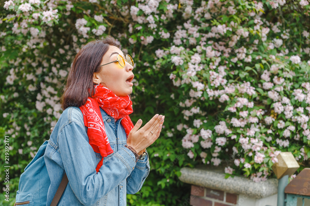 Allergy concept. Young asian woman sneezes and blowing her nose with a handkerchief and suffering in the spring among flowering and blooming trees. Allergy concept. Young asian woman sneezes and blowing her nose with a handkerchief and suffering in the spring among flowering and blooming trees.