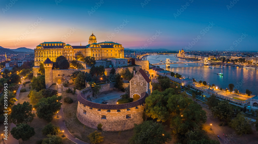 Fototapeta premium Budapeszt, Węgry - Panoramiczny widok z lotu ptaka na piękny oświetlony Pałac Królewski w Budzie z mostem łańcuchowym Szechenyi, węgierski parlament w niebieskiej godzinie