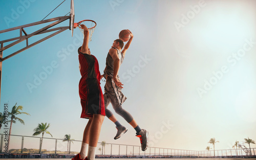 Streetball. Basketball player in action on sunset.