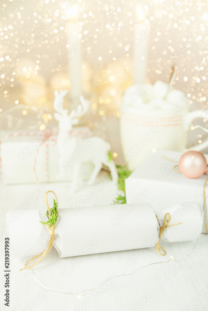 White Winter Decoration in Scandinavian Style. Mock up Wrapped Gift Boxes Twine Juniper Twigs. Lit Candles Deer Sparkling Garland Lights Mug with Hot Chocolate Marshmallows. Festive Atmosphere White Winter Decoration in Scandinavian Style. Mock up Wrapped Gift Boxes Twine Juniper Twigs. Lit Candles Deer Sparkling Garland Lights Mug with Hot Chocolate Marshmallows. Festive Atmosphere