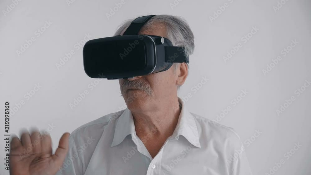 Senior man using his VR headset for watching the 360 video at white background Senior man using his VR headset for watching the 360 video at white background