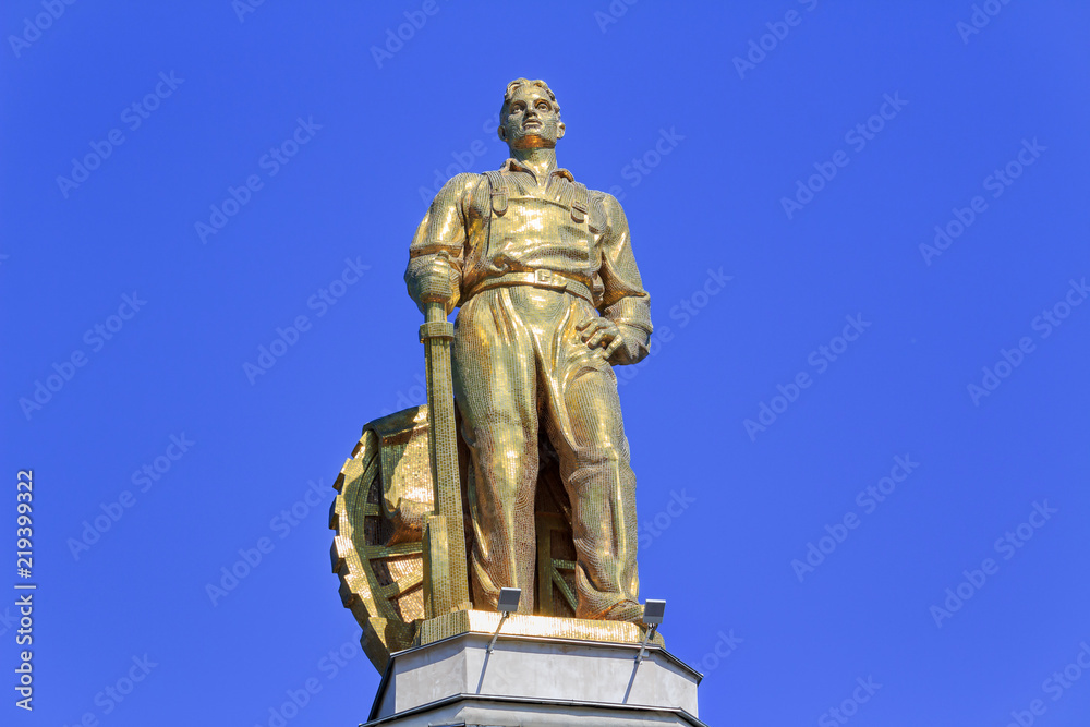 Figure of man tractor driver on a roof of pavilion Space on VDNH in Moscow on a blue sky background in sunny summer morning