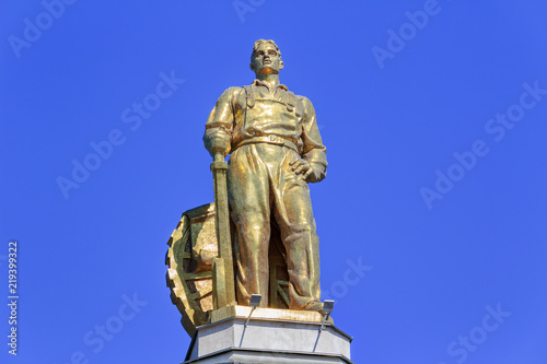 Figure of man tractor driver on a roof of pavilion Space on VDNH in Moscow on a blue sky background in sunny summer morning