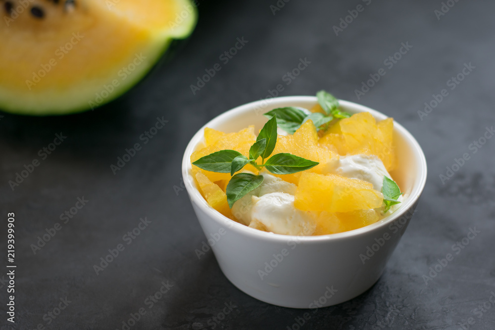 Pieces of yellow watermelon with ice cream in a white cup Pieces of yellow watermelon with ice cream in a white cup