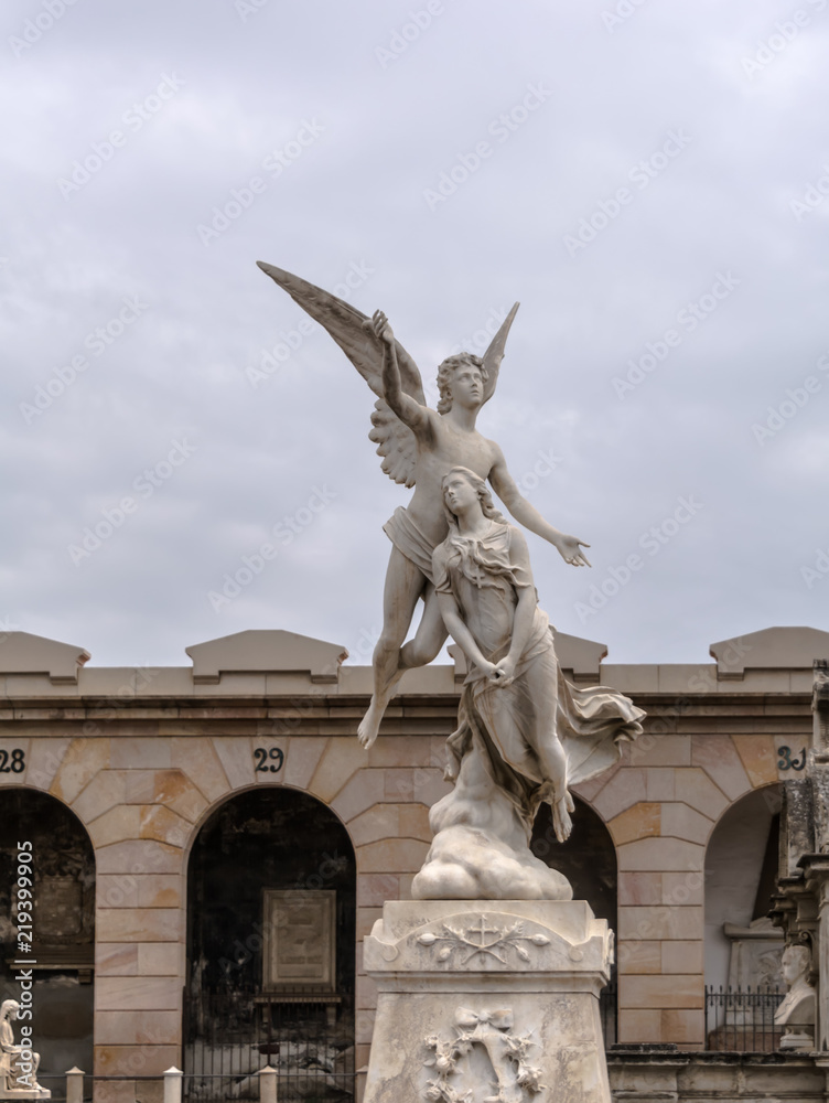 Barcelona, Spain - May 10, 2018: Neoclassic sculpture of a winged angel raising the swooning soul of a maiden to heaven. The statue, carved by Fabiesi, dates to 1880, and located in Poblenou Cemetery.