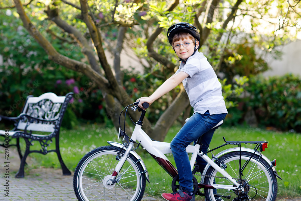 Happy school kid boy having fun with riding of bicycle. Active healthy child with safety helmet making sports with bike in nature. Safety, sports, leisure with kids concept