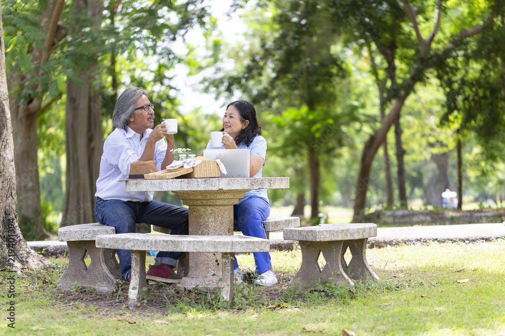 Happy Asian senior couple or friends talking and drinking coffee or tea relaxing while using laptop computer,social network at garden or nursing home. Happy Retirement Senior Lifestyle Living Concept Happy Asian senior couple or friends talking and drinking coffee or tea relaxing while using laptop computer,social network at garden or nursing home. Happy Retirement Senior Lifestyle Living Concept