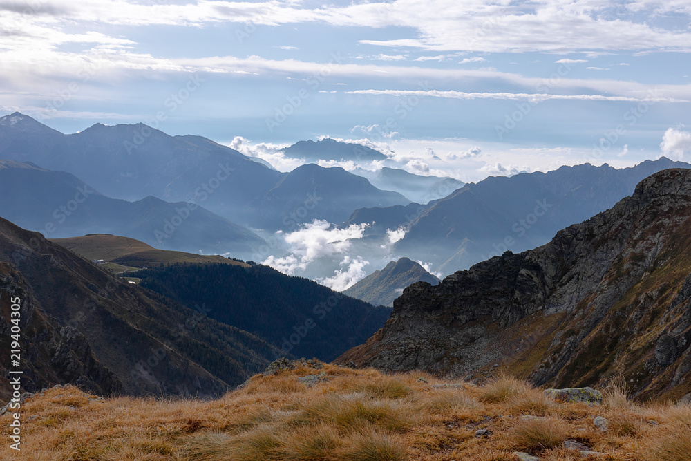 A stunning autumn landscape of the Italian Alps covered with morning fog