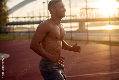 Fitness training outdoors. Handsome man working exercises in early morning with sunrise. Muscular man training outside. Sunny fitness morning.