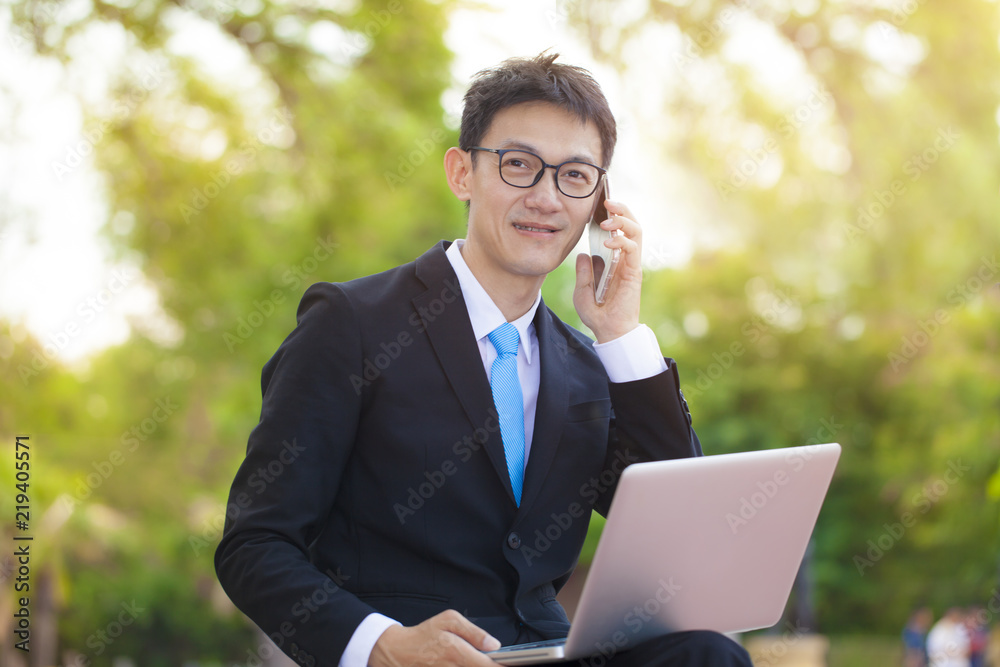 Young businessman in white shirt, classic suit, eyeglasses. Man sit on soft pouf with laptop pc computer, Mobile business concept. Young businessman in white shirt, classic suit, eyeglasses. Man sit on soft pouf with laptop pc computer, Mobile business concept.