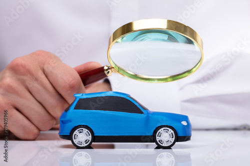 Businessman Holding Magnifying Glass Over Car