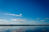 Blue sky with clouds over Lake Ladoga. Beautiful landscape with deep blue sky and quiet lake without excitement.