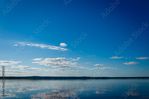 Blue sky with clouds over Lake Ladoga. Beautiful landscape with deep blue sky and quiet lake without excitement.