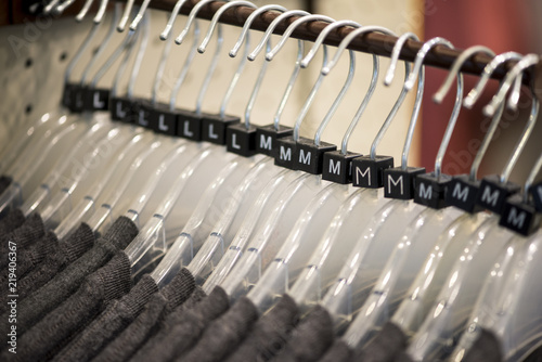 Plastic clothes hangers on rack, different sizes, selective focus on Medium size M