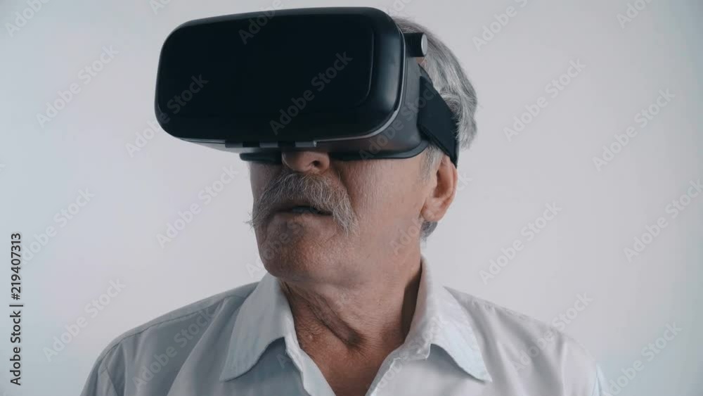 Senior man using his VR headset for watching the 360 video at white background Senior man using his VR headset for watching the 360 video at white background
