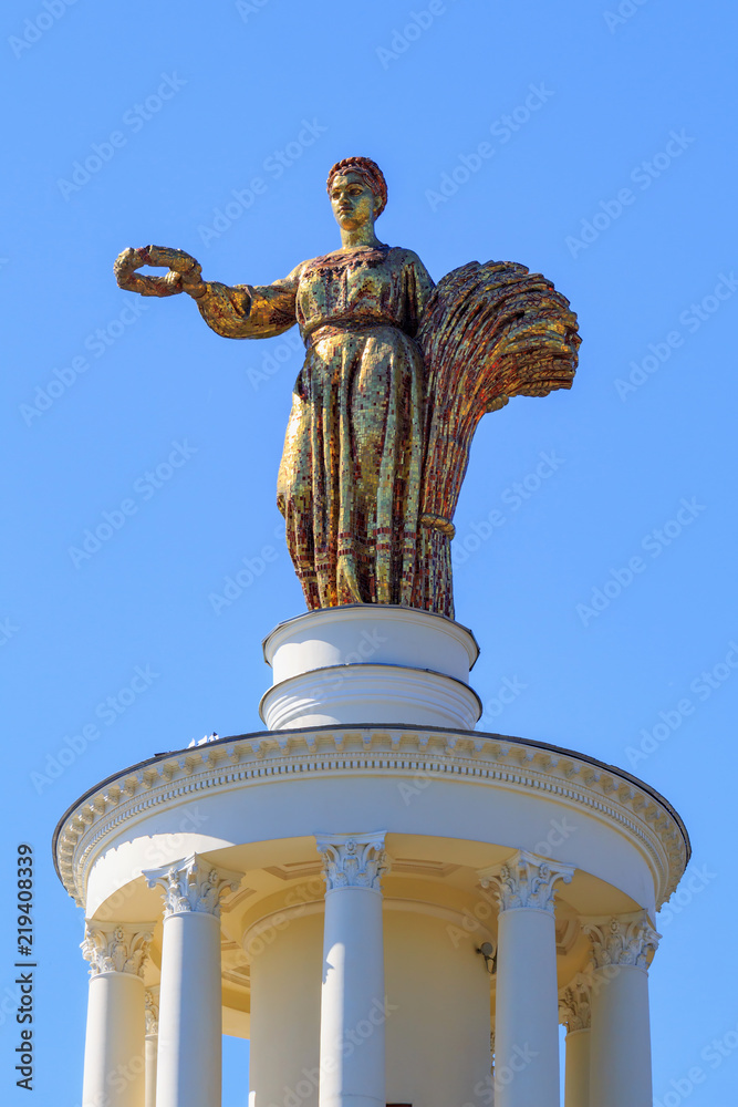 Obraz premium Figure of woman of collective farmer with sheaf and wreath on a roof of pavilion Republic Of Belarus on Exhibition of Achievements of National Economy (VDNH) in Moscow