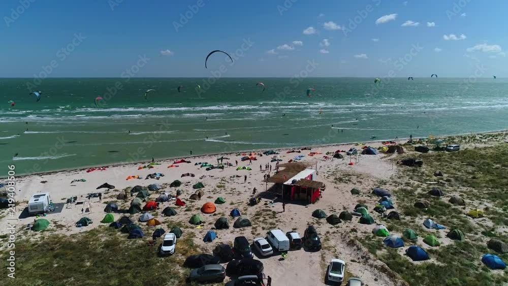Training kites in the sea and bright piloting kites in the sea, many people are resting on the beach. Slow motion Training kites in the sea and bright piloting kites in the sea, many people are resting on the beach. Slow motion