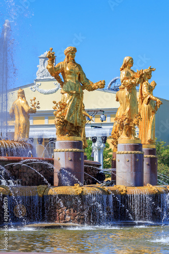 Gilded bronze girls symbolizing Republics of USSR in fountain Friendship of peoples on VDNH in Moscow on a blue sky background in sunny summer morning