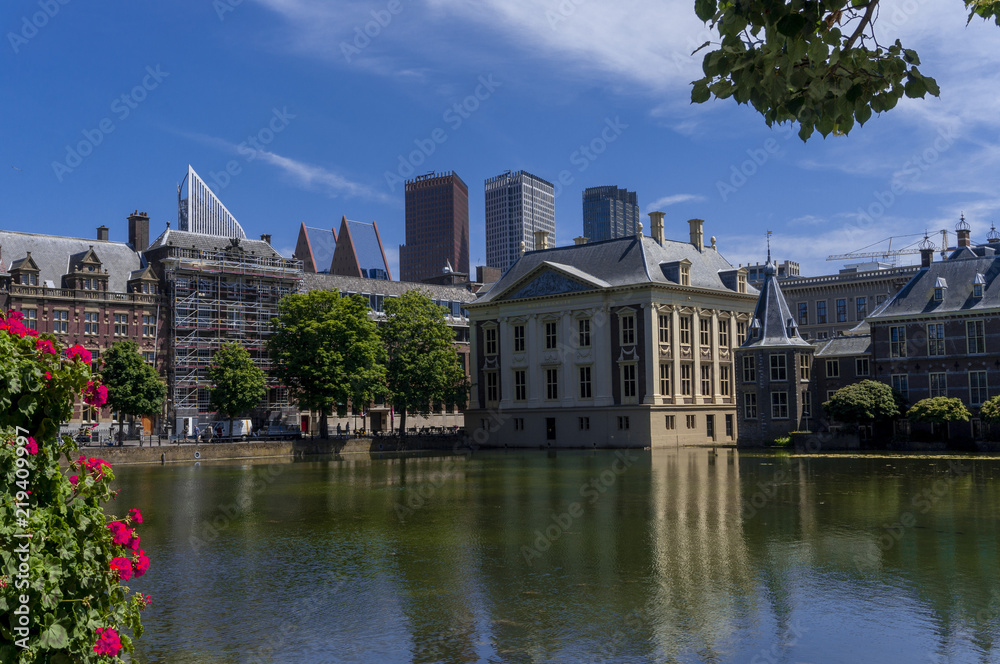 Skyline of The Hague with the modern office buildings behind the Mauritshuis museum and the Binnenhof parliament building next to Hofvijver lake. 