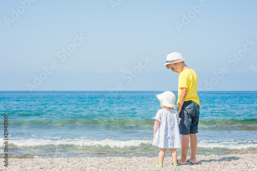 Boy and girl standing holding hands on the beach on summer holidays. concept of summer family vacation. Space for text