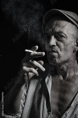 An elderly man in a cap and with a cigarette.