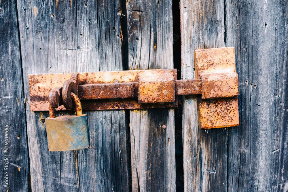 Old rusty latch with padlock on wooden doors Old rusty latch with padlock on wooden doors