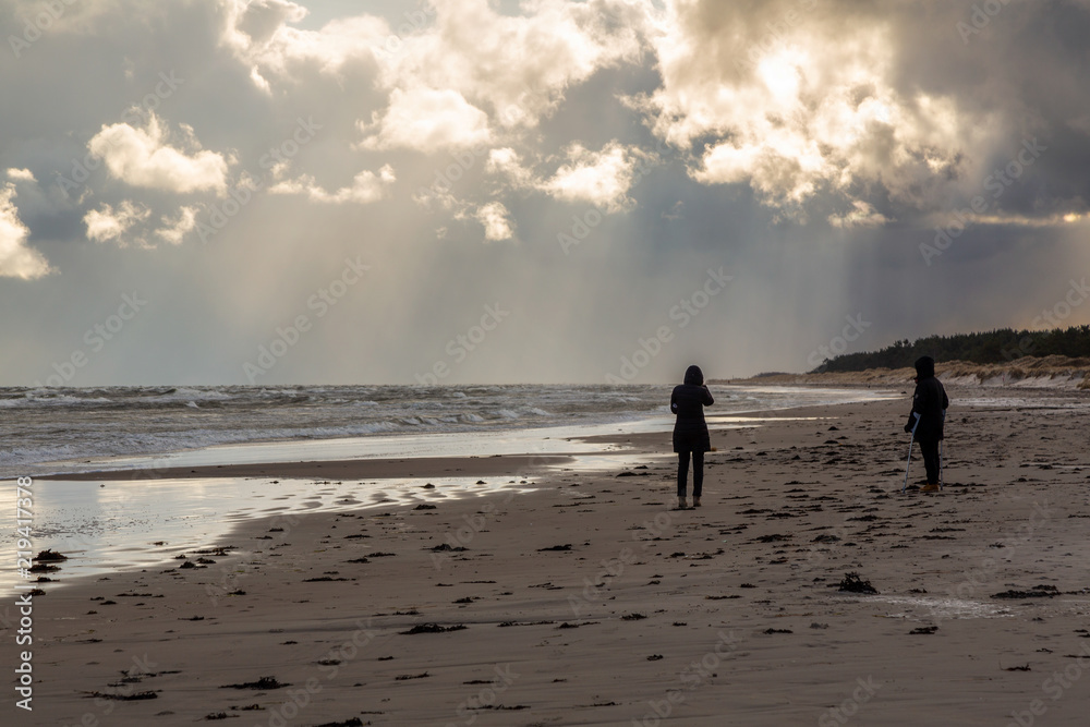 Man och kvinna promenerar på en kall och blåsig strand