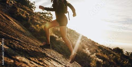 Fototapeta Woman running up a rocky mountain slope