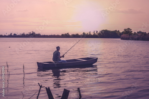 fishing-fisherman fishing on bank of river at sunset.