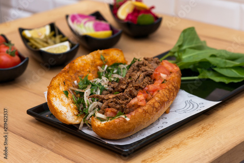 Authentic Turkish Tantuni kebab sandwich with beef and fresh herbs, traditional street food served with pickles and salad