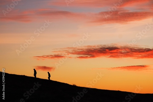  2 Silhouette persons Walking Up Hill Mountain Climb Sunset
