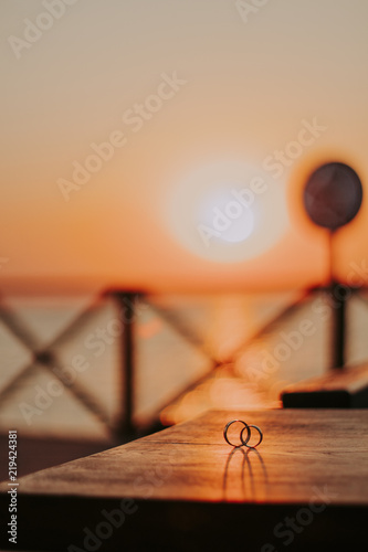 Wedding rings on a beautiful wooden texture surface against the sunset sun