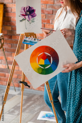 painting creativity and skills improvement. woman holding a watercolor palette or color wheel. drawing techniques mastering at art school. photo