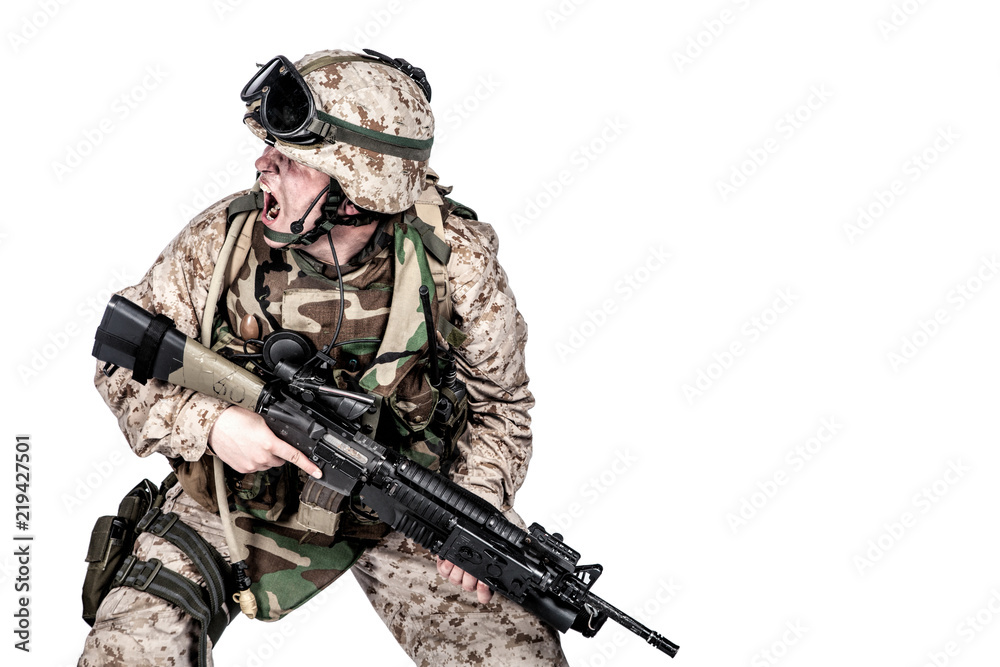 Studio shoot of modern infantry soldier, U.S. marine rifleman in combat uniform, helmet and body armor, screaming and crouching down with assault service rifle in hands isolated on white background Studio shoot of modern infantry soldier, U.S. marine rifleman in combat uniform, helmet and body armor, screaming and crouching down with assault service rifle in hands isolated on white background