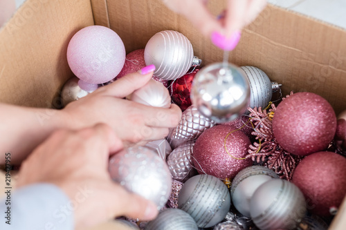 family christmas home decoration traditions. man and woman taking out rose gold and silver glittery balls from a box. holiday festive ornament concept. photo