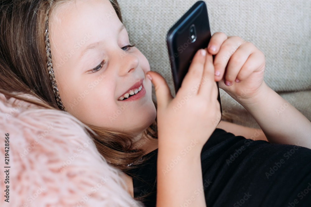 child leisure and entertainment. technology and digital devices in kids upbringing. happy smiling girl playing games on mobile phone. child leisure and entertainment. technology and digital devices in kids upbringing. happy smiling girl playing games on mobile phone.