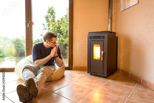 Mann sitzt im riesigen Kissen auf dem Boden und wärmt sich am Ofenfeuer