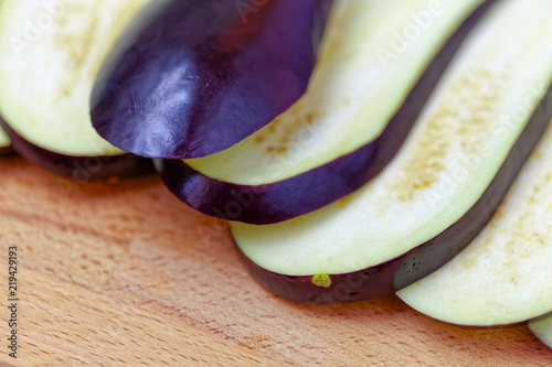 Aubergine or eggplant with slices on wooden background. Close up view.