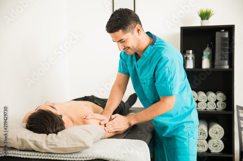 Therapist Massaging The Injured Shoulder Of Athlete In Hospital photo