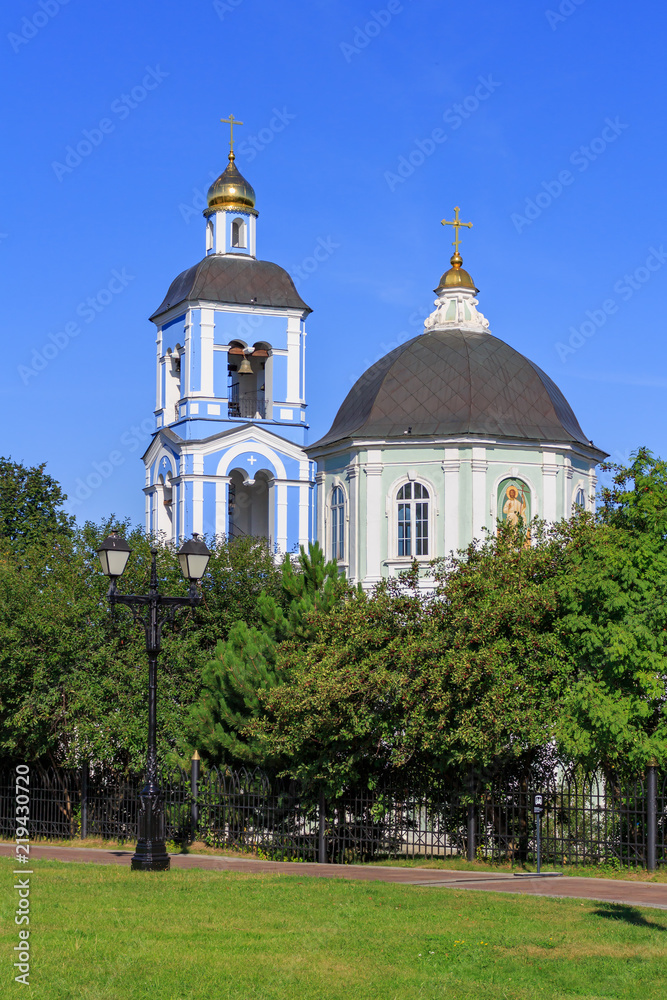 Golden domes of Temple of the icon of Our Lady Life-giving Source in Museum-reserve Tsaritsyno in Moscow on a blue sky and green trees background in sunny summer morning
