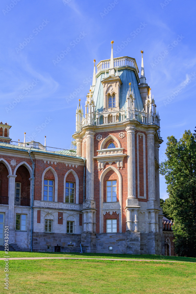 Tower of Great Palace in Museum-reserve Tsaritsyno in Moscow on a green lawn and blue sky background at sunny summer morning