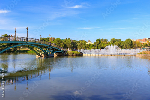 View of bridge to the island Horseshoe and light and music fountain from embankment of Middle Tsaritsynsky pond in Museum-reserve Tsaritsyno in Moscow on a sunny summer morning